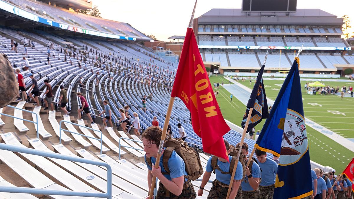 Individuals carrying flags up on the steps of Kenan stadium.